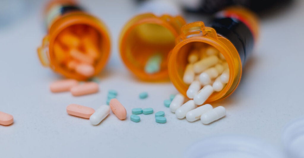 Three pill bottles spilled on a white table.