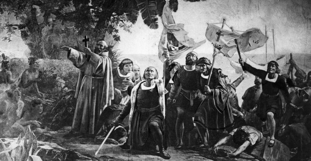 Black and white rendering of a painting of Christopher Columbus, kneeling, surrounded by fellow travelers, after landing.