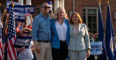 Jay Jones, Abigail Spanberger and Ghazala Hashmi link arms during a campaign rally.