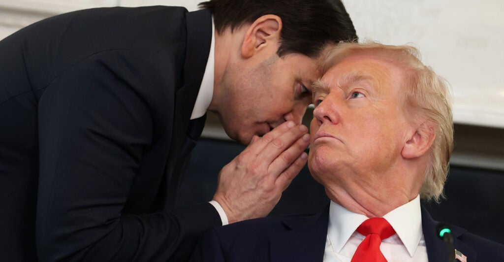 U.S. Secretary of State Marco Rubio whispers something in President Donald Trump’s ear.