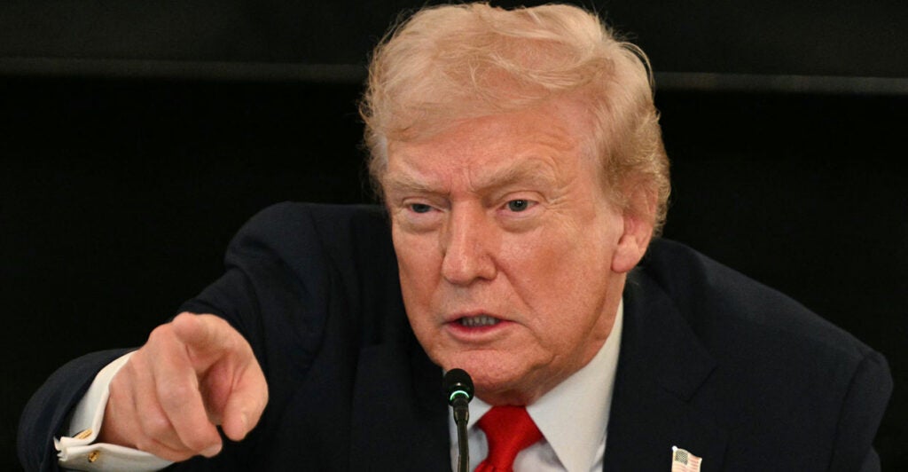 Close-up of Donald Trump pointing, against a black background.