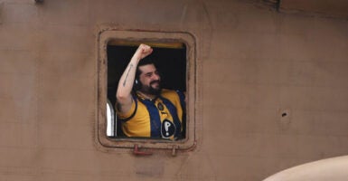 Former hostage Ziv Berman in the window of a helicopter, his fist pumped, celebrates his freedom.