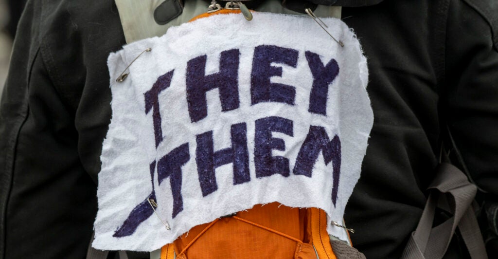 White arm band with black lettering, reading "They Them."