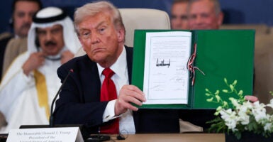 Donald Trump holds up signed Middle East peace deal.