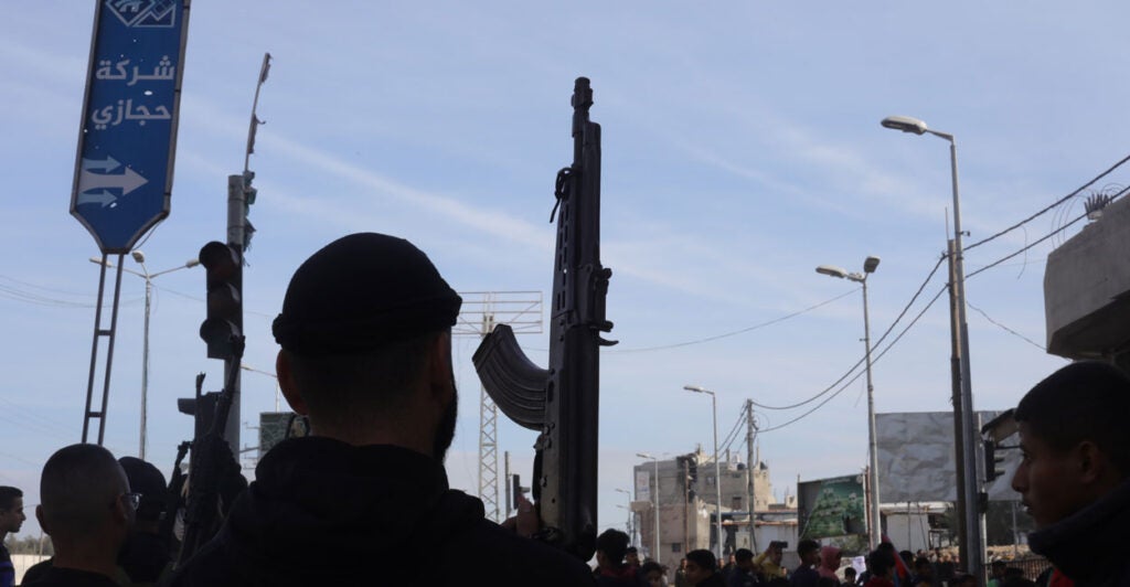 Silhouette of man with a gun against blue sky.