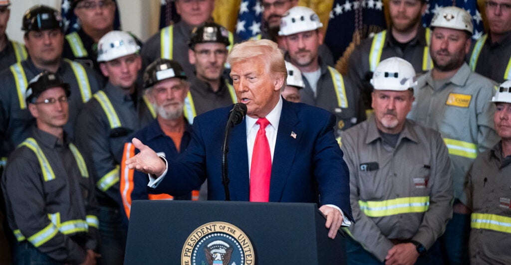 Trump at podium in White House surrounded by coal workers.