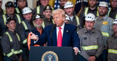 Trump at podium in White House surrounded by coal workers.