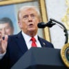 President Trumps speaks at a lectern in a dark suit and red tie.