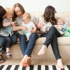 Three mothers sit with four little children on a couch.