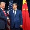 President Donald Trump and Chinese leader Xi Jinping shake hands in front of Chinese and American flags.