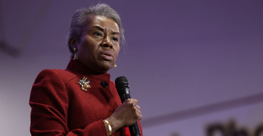 Winsome Sears in a red suit holding a microphone