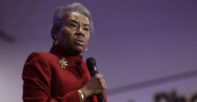 Winsome Sears in a red suit holding a microphone