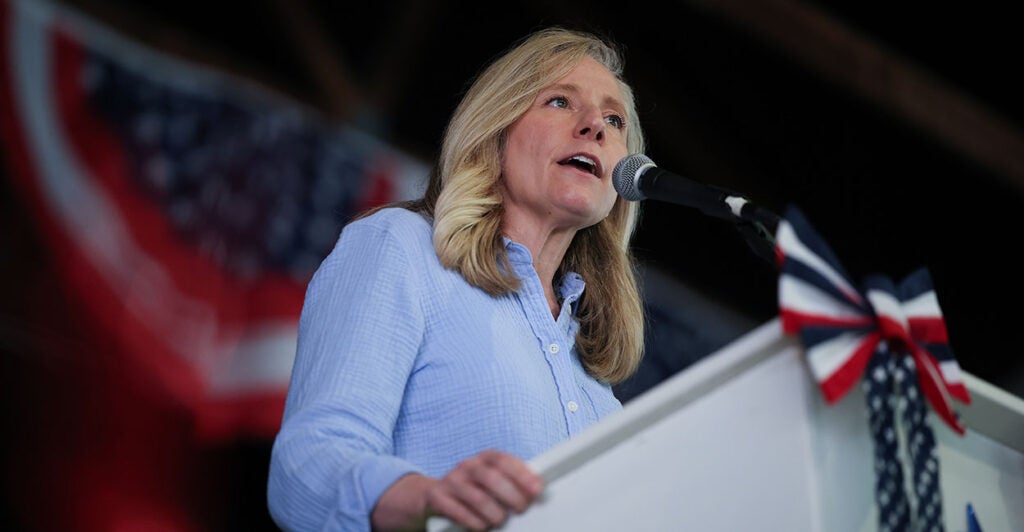 Abigail Spanberger behind a podium with American flags
