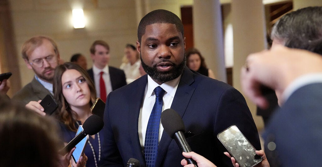 Byron Donalds in a blue suit with a blue tie answers questions from press.