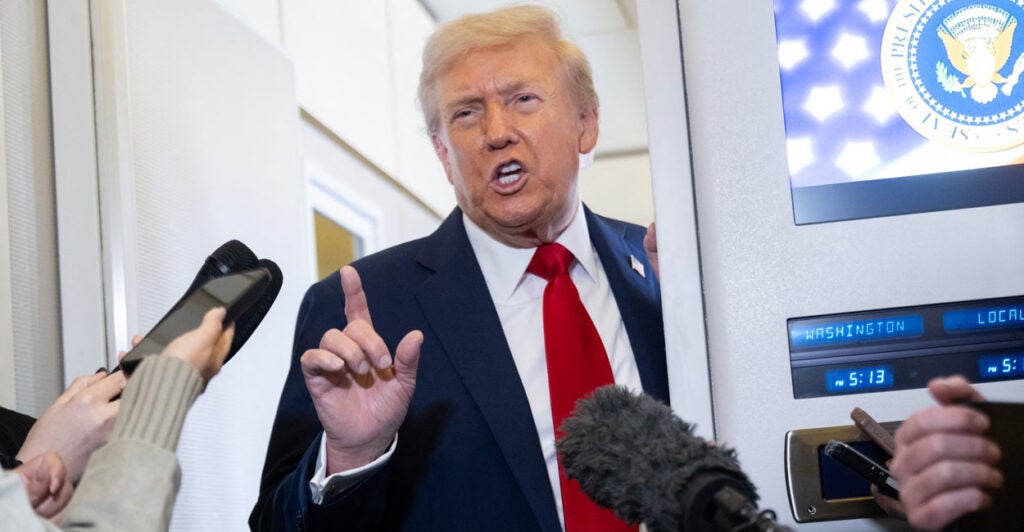 President Donald Trump speaks to reporters aboard Air Force One on Monday.
