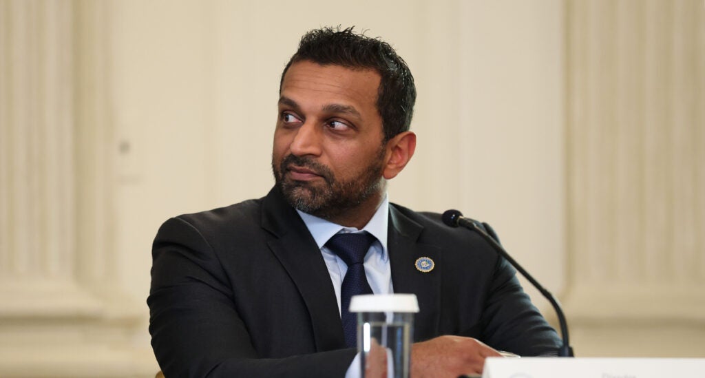 FBI Director Kash Patel is sitting and looking to his right.