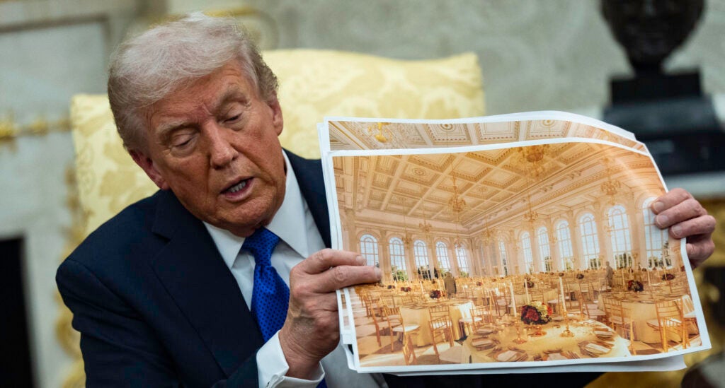 President Donald Trump speaks holding a photos of the new ballroom during a meeting with NATO Secretary General Mark Rutte in the Oval Office of the White House in Washington, DC on October 22, 2025.