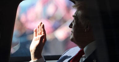President Donald Trump waves from his official vehicle known as
