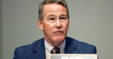 Sen. John Husted sits at a podium.