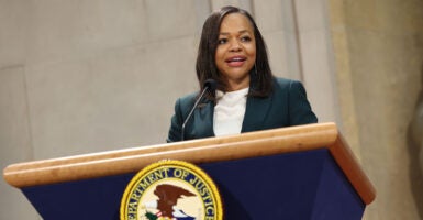 Kristen Clarke in a suit behind a Justice Department seal.