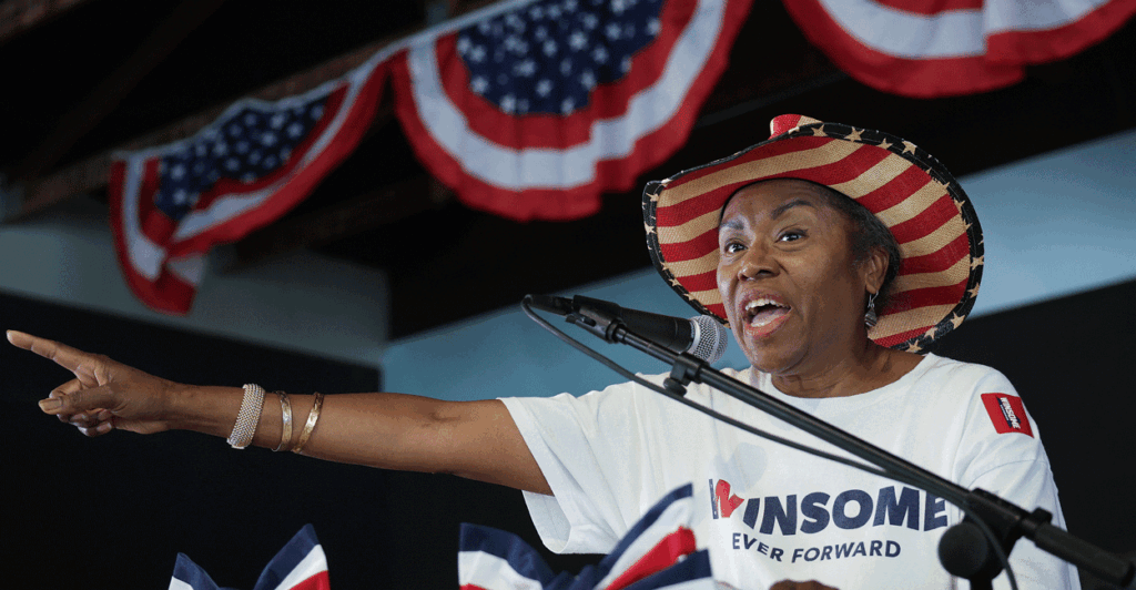 Winsome Earle-Sears on stage at a rally wearing an American flag cowboy hat.