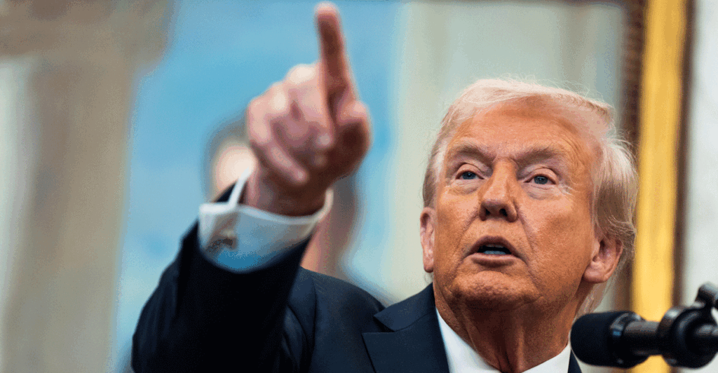 President Donald Trump points to the press answering questions in the oval office.