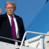 President Trump boarding Air Force One wearing a purple tie with his fist in the air