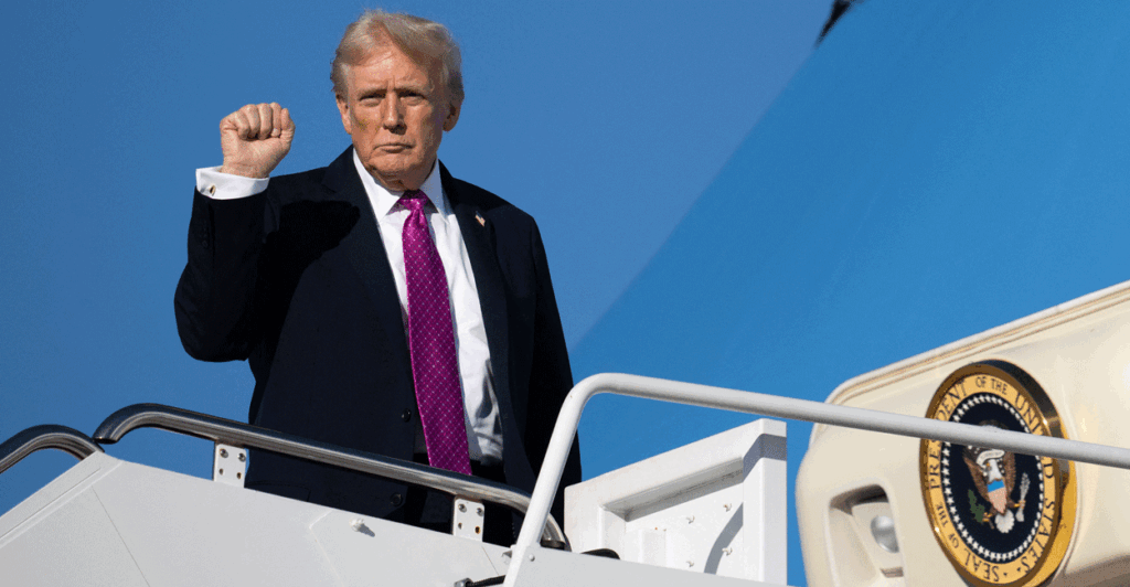 President Trump boarding Air Force One wearing a purple tie with his fist in the air