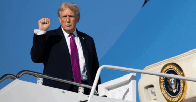 President Trump boarding Air Force One wearing a purple tie with his fist in the air