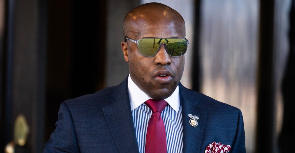 Wesley Hunt, wearing a suit and reflective sunglasses, exits the Capitol Hill Club in Washington, D.C.