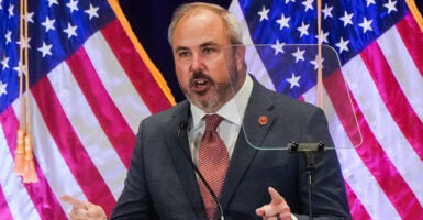 RNC Chairman Joe Gruters speaks in front of American flags.
