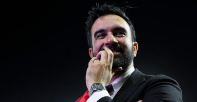 Close-up of Zohran Mamdani with his hand at his face.