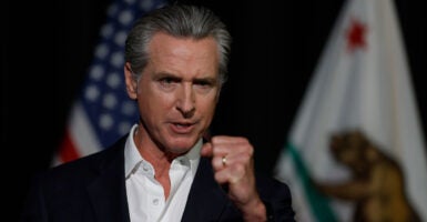 Governor Gavin Newsom in a suit without a tie speaking to an audience gesturing with his fist
