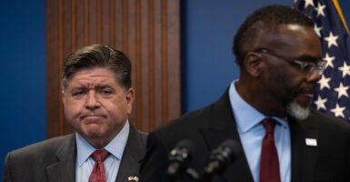 Illinois Gov. JB Pritzker standing behind Chicago Mayor Brandon Johnson at press conference.