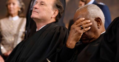 U.S. Supreme Court Associate Justices Samuel Alito (L) and Clarence Thomas wait for their opportunity to leave the stage.