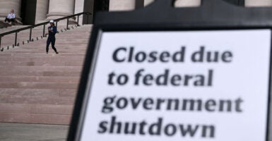 A sign outside the steps of a federal building that says closed due to federal government shutdown