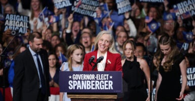 Abigail Spanberger stands before a podium and smiles while leaning her head to the left.