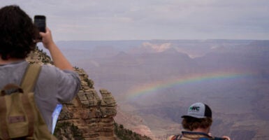 Tourists watch a rainbow at the Grand Canyon.