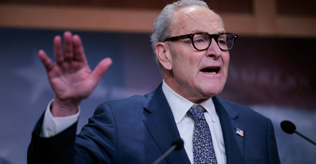 Chuck Schumer with hand raised.