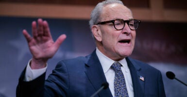 Chuck Schumer with hand raised.