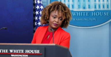 Karine Jean-Pierre at White House podium in red suit.