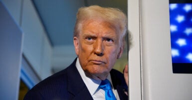 Donald Trump leans against a door frame on Air Force One.