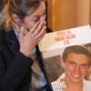 Ayelet Kaufman, sister of slain Israeli soldier Hadar Goldin, holds his picture and wipes away a tear while speaking to the media.