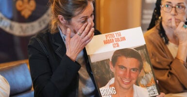 Ayelet Kaufman, sister of slain Israeli soldier Hadar Goldin, holds his picture and wipes away a tear while speaking to the media.