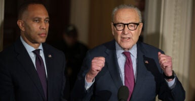 Chuck Schumer, with fists raised, speaks to reporters, with Hakeem Jeffries at his side.