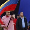 Venezuelan President Nicolas Maduro in a pink shirt waves Venezuelan flag.