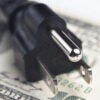 An electric plug atop a $100 bill.