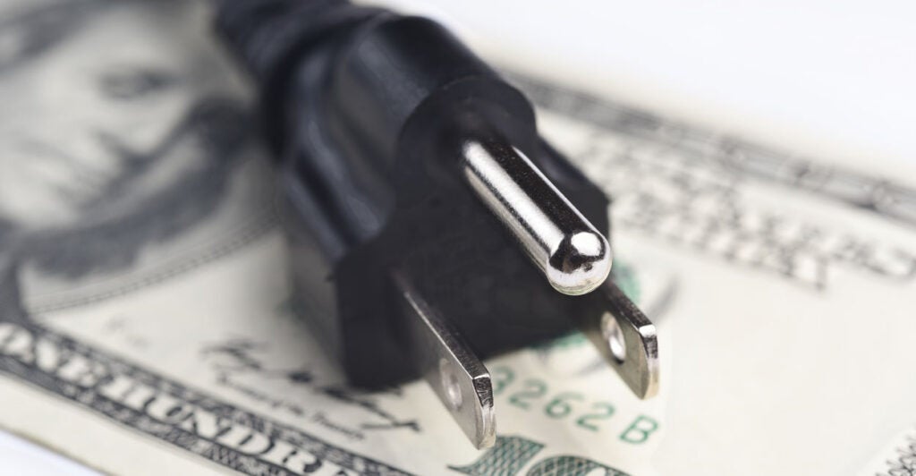 An electric plug atop a $100 bill.
