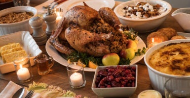 A Thanksgiving feast is spread across a table, with mouthwatering turkey in the center.