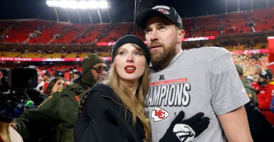 Taylor Swift holds onto Travis Kelce on the field after a Kansas City Chiefs game.